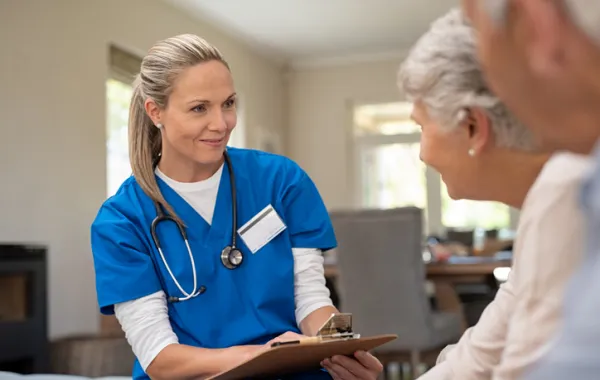 Foto de una trabajadora social atendiendo a una pareja de personas mayores