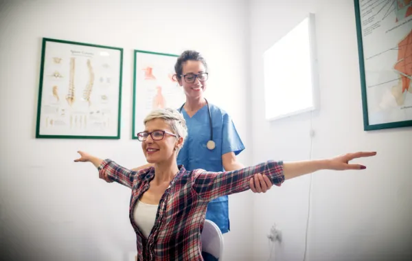 Foto de una mujer haciendo ejercicio acompañada por una fisioterapeuta