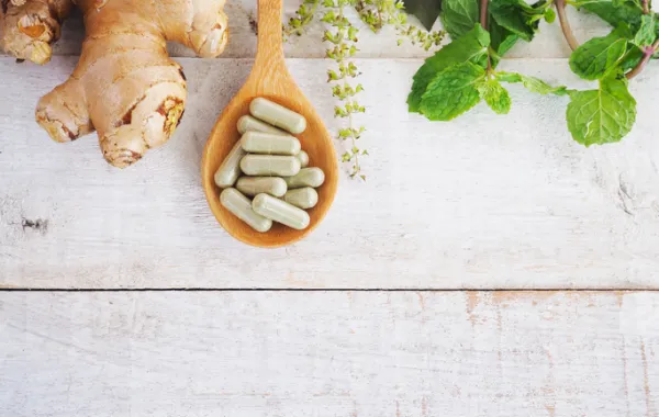 Foto de una cuchara con píldoras de suplementos alimenticios y un raíz de jengibre