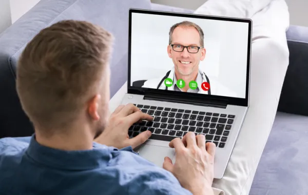 Foto de una joven mirando en su portátil a un médico