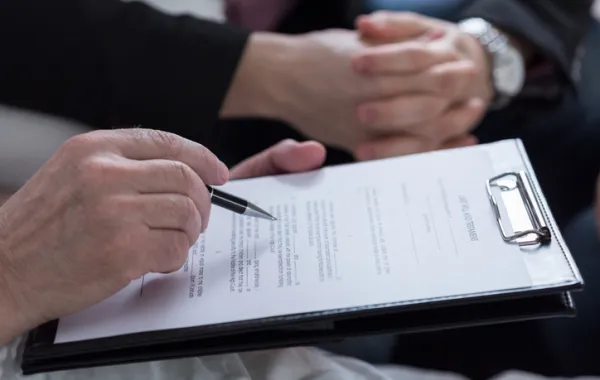 Foto de una mano de una persona mayor que firma un documento