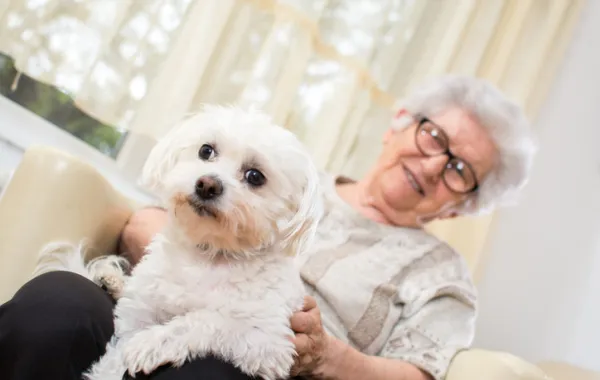 Foto de una mujer mayor sonriendo y acompañada por un perro