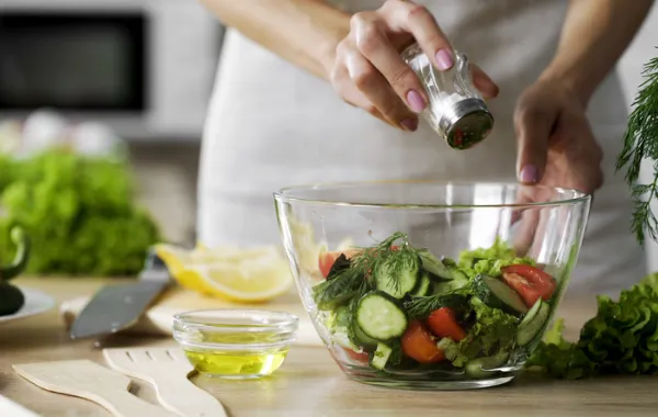 Foto de una persona echando sal en una ensalada