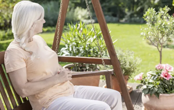 Foto de una mujer mayo sentada en una mesa en el jardin