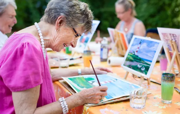 Foto de mujeres mayores sentadas mientras pintan un cuadro 