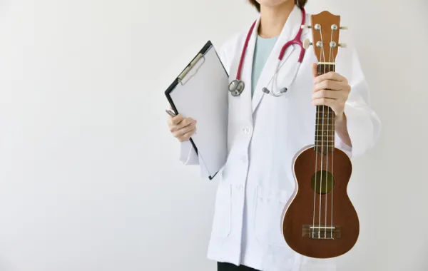 Foto de una doctora que sujeta con la mano una guitarra