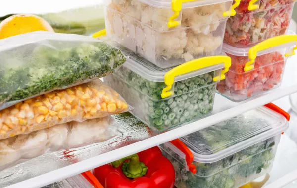 Foto de recipientes con verduras congeladas en un congelador