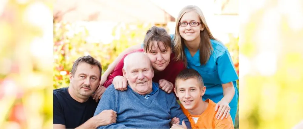 Foto de un abuelo rodeado de su familia en referencia a familias cuidadoras