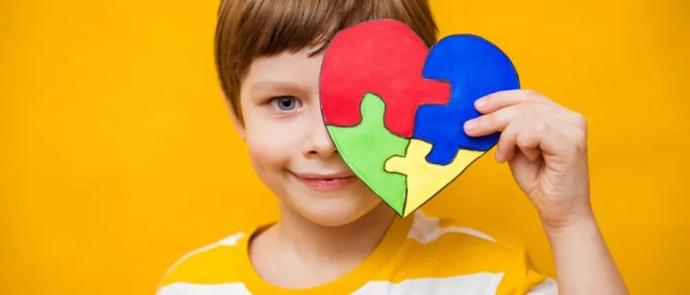 Foto de un niño sosteniendo un corazon hecho con piezas de puzzle