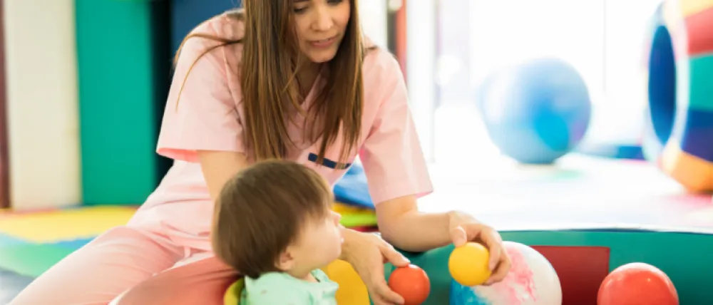 Foto de una madre jugando con un niño pequeños con una piscina pequeña de bolas