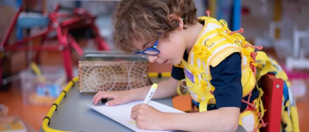 Foto de Fundación NIPACE con un niño con parálisis cerebral escribiendo