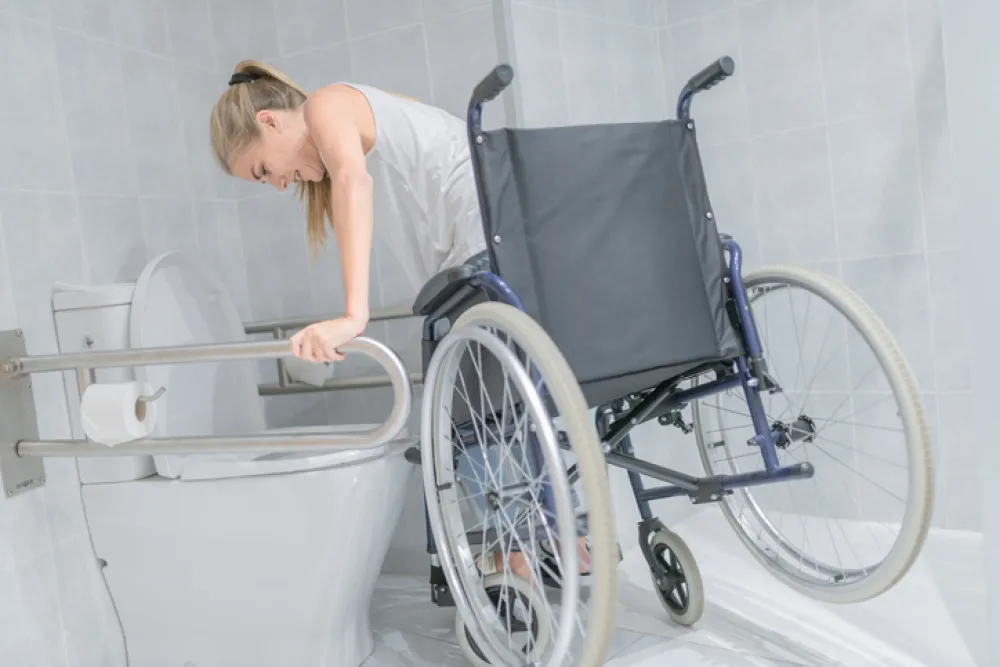 Foto de una mujer joven en silla de ruedas accediendo a un baño publico accesible