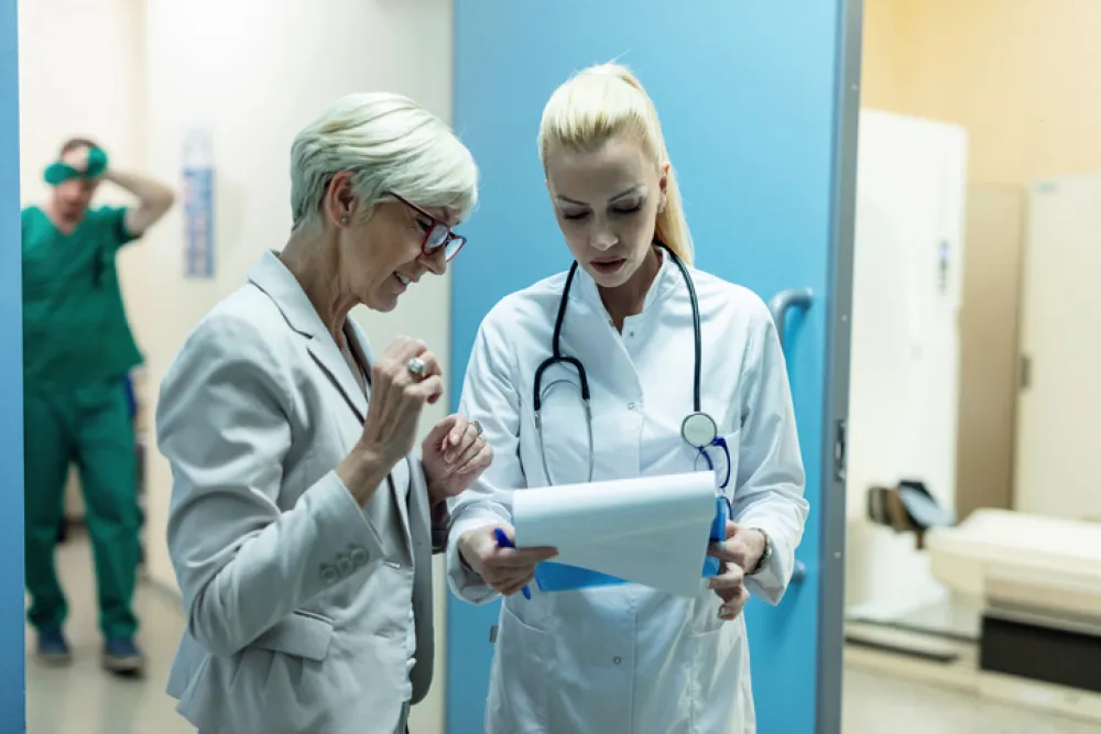 Foto de dos doctoras que conversan mientras observan un informe médico