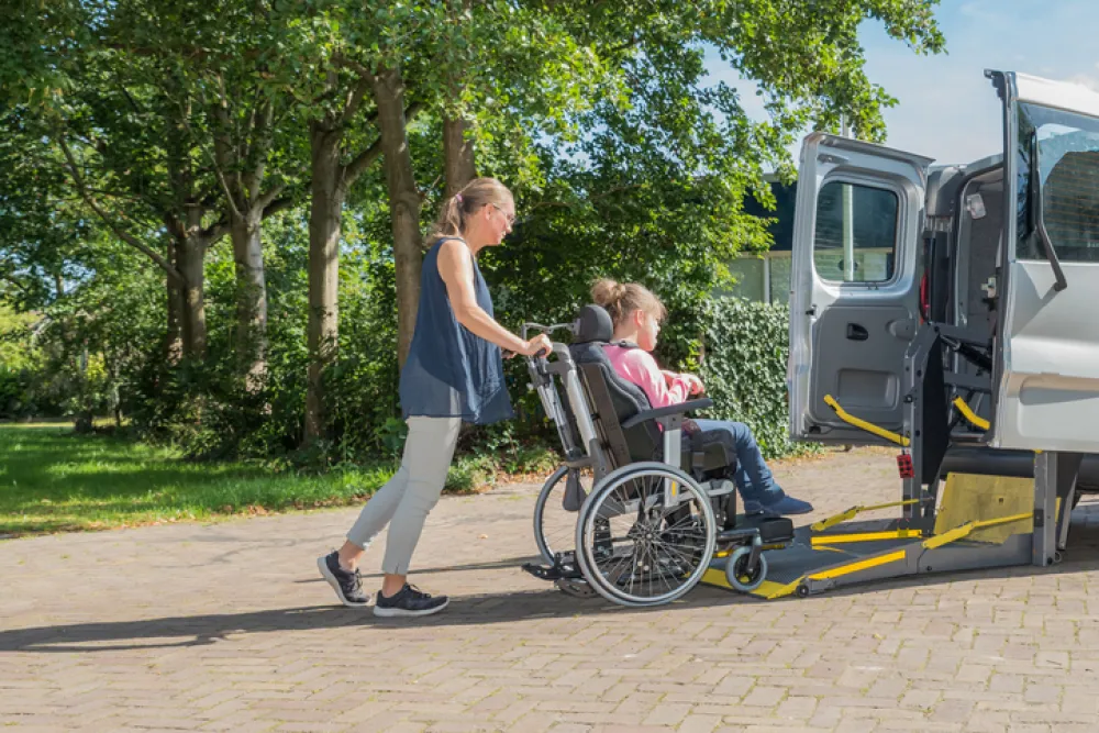 Foto de una mujer que ayuda a subir a una mujer en silla de ruedas a una furgoneta especial