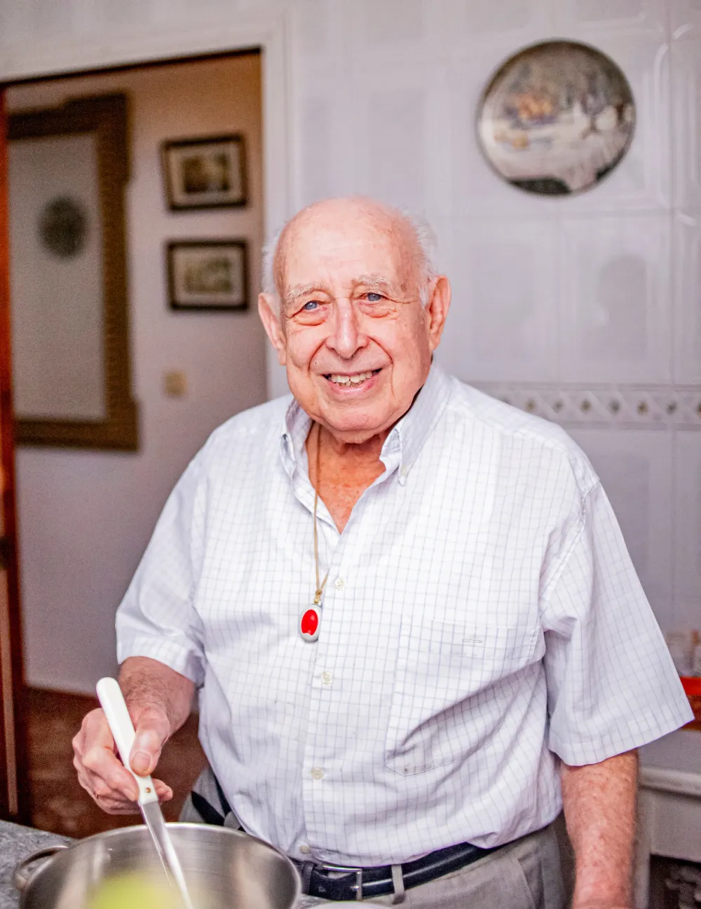 Foto de un señor mayor cocinando y mirando a cámara sonriente