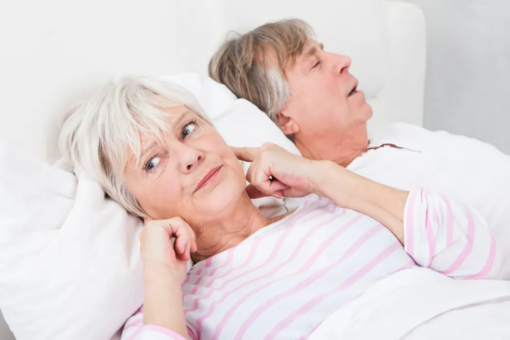 Foto de una pareja durmiendo mientras una mujer se tapa los oidos