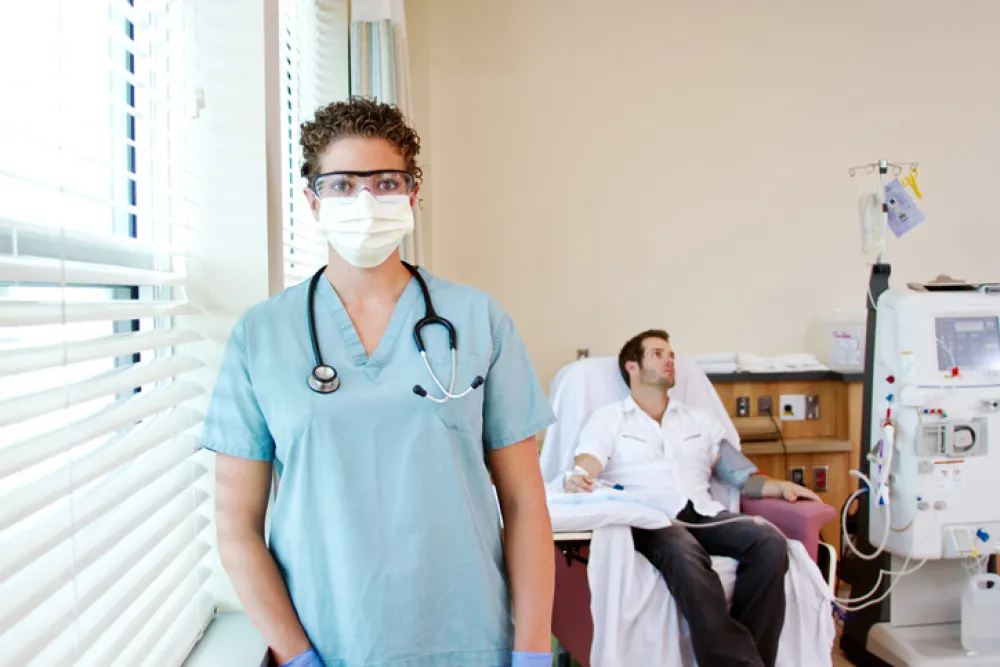 Foto de un enfermo recibiendo tratamiento y delante de él la doctora que lo cuida
