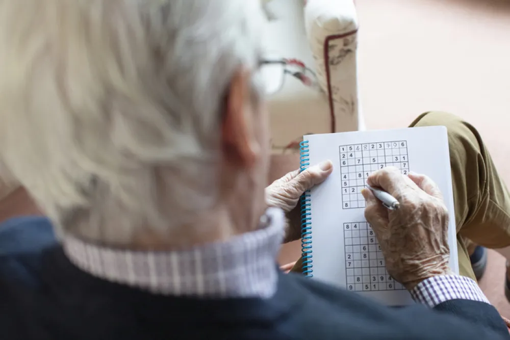 Foto un señor mayor que está haciendo un sudoku
