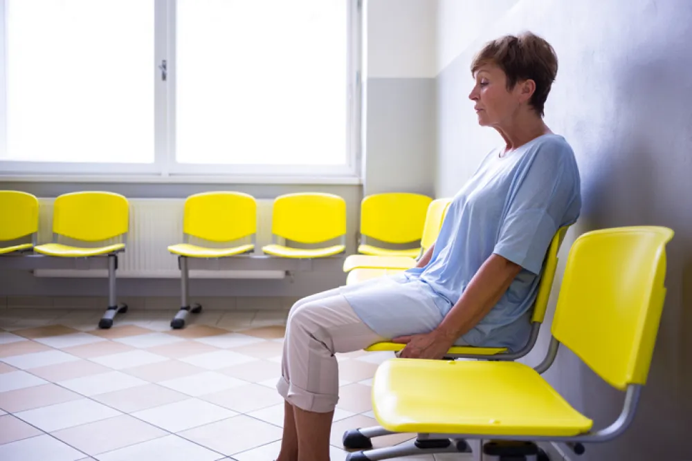 Foto de una mujer mayor sentada en una silla de una sala de un hospital