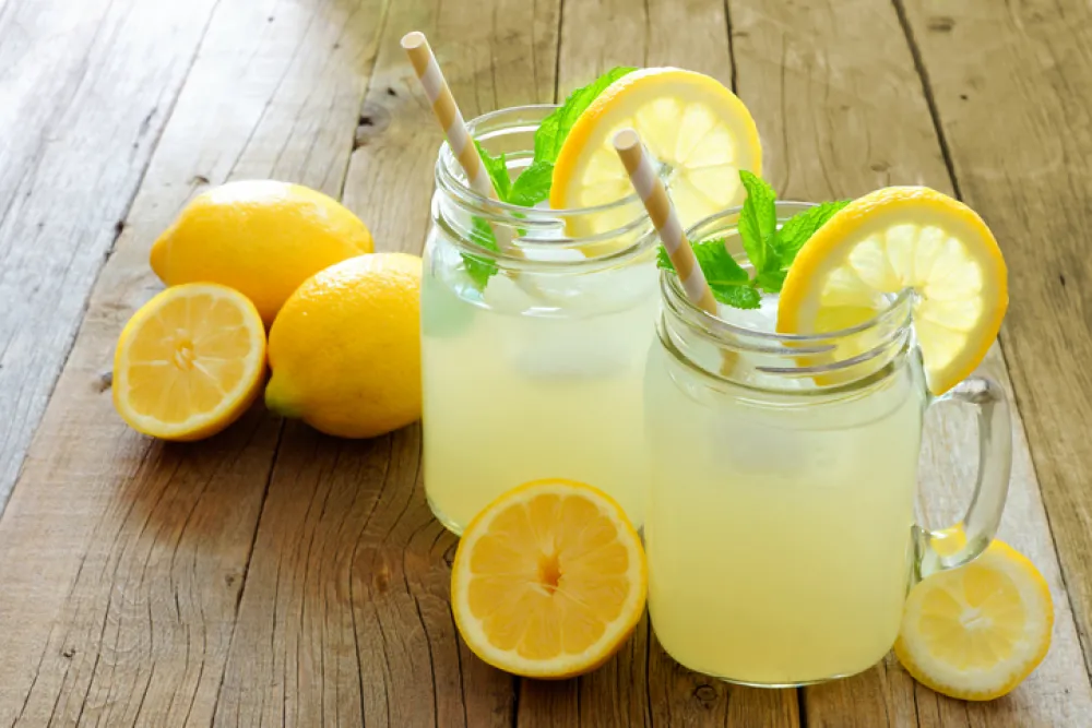 Foto con dos vasos de granizado de limon rodeados de limones