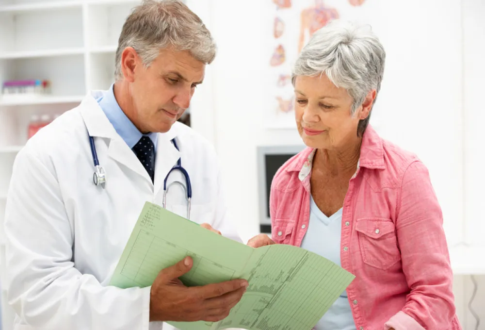 Foto de una mujer mayor acompañada de un médico que le muestra unos documentos