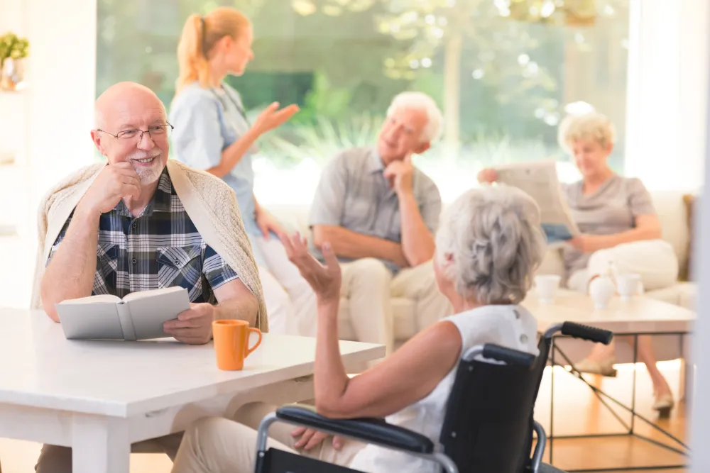 Foto de varias personas mayores charlando en un salón de una residencia