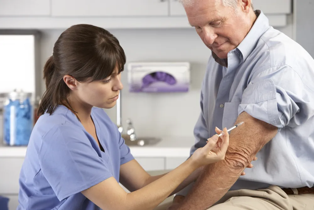 Foto de una enfermera poniendo una vacuna a un señor mayor