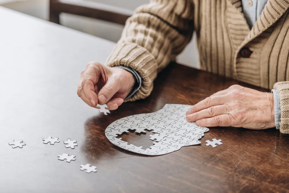 Foto de unas manos de persona mayor haciendo un puzle