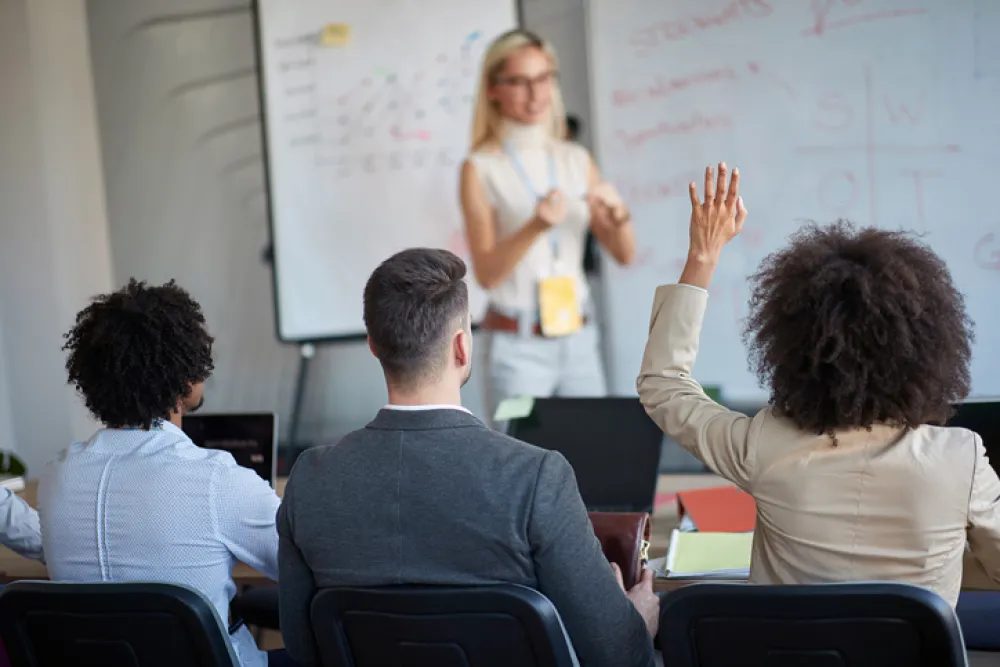 Foto de un aula con la profesora impartiendo un curso a varios alumnos