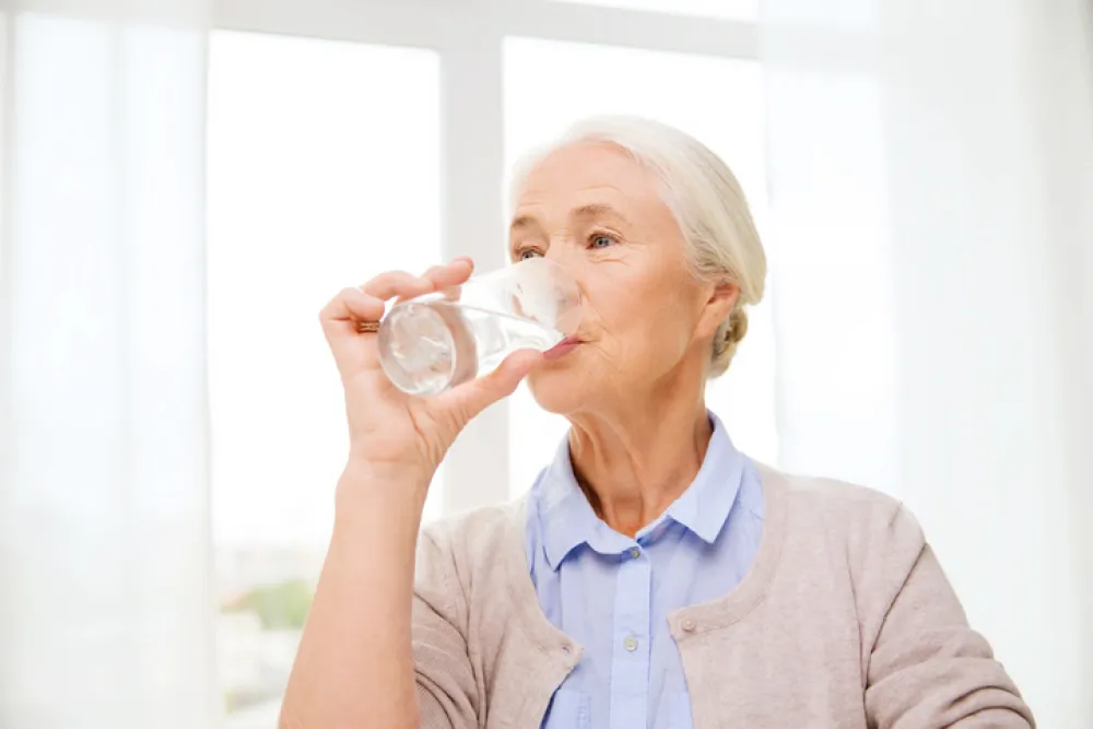 Foto de una mujer mayor bebiendo un vaso de agua