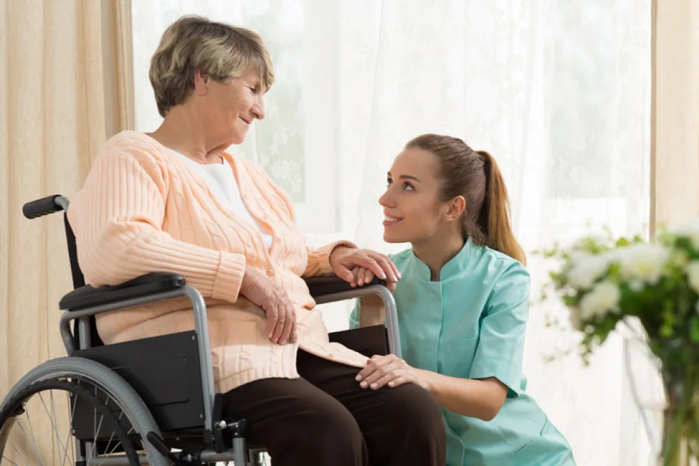 Foto de mujer mayor en silla de ruedas acompañada de una enfermera