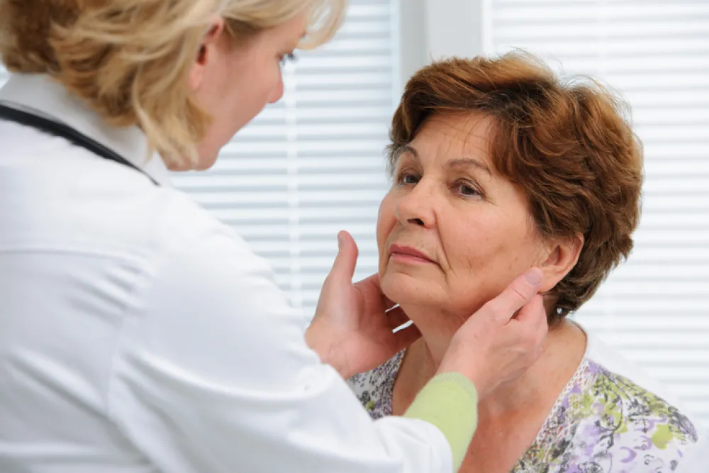 Foto de una doctora palpando el cuello de una señora por la zona de las tiroides