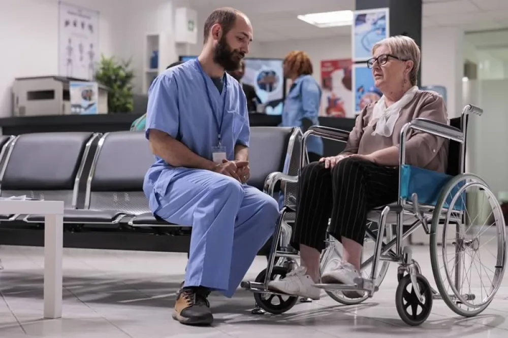 Foto de un trabajador de la salud con una paciente en silla de ruedas