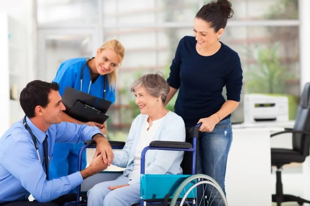 Mujer sonriente en silla de ruedas acompañada por familiares y personal médico