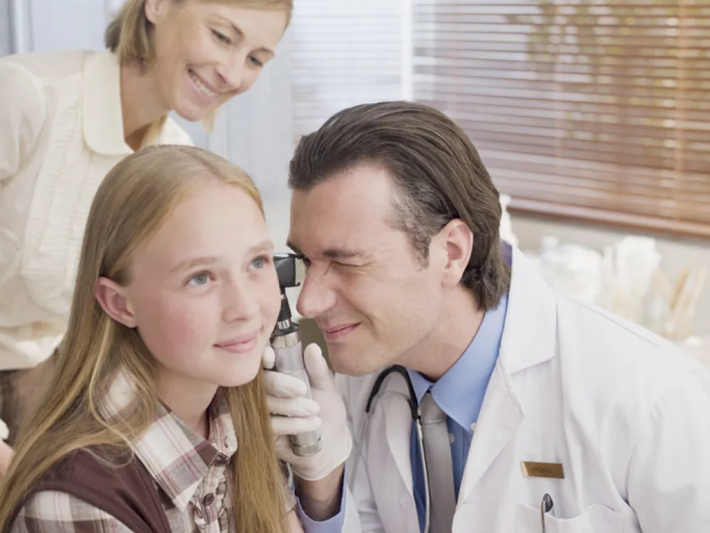 Foto de médico que observa el interior del oído de una niña
