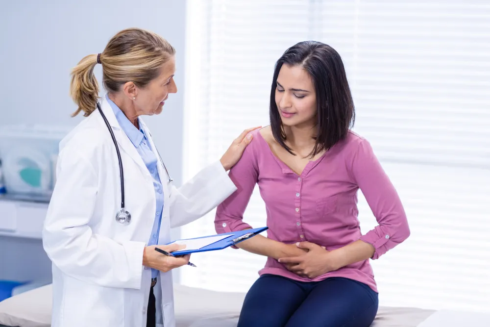 Foto de mujer con dolor en el estómago acompañada de una doctora