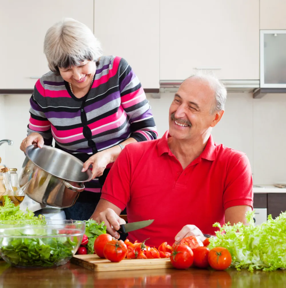 Foto pareja personas mayores preparando una ensalada y sonriendo