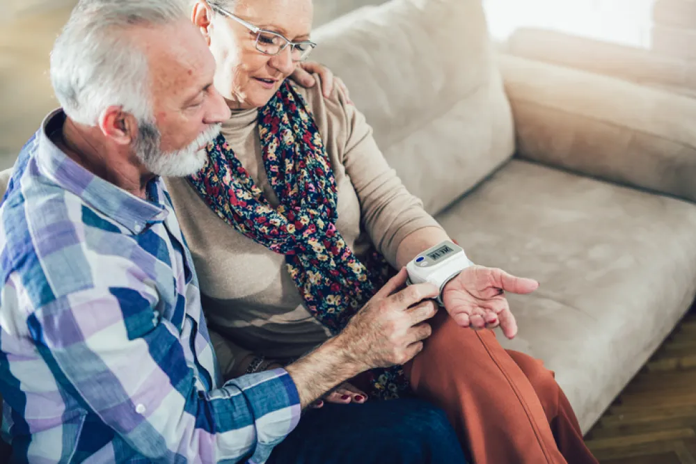 Foto de un pareja de personas mayores mirando un dispositivo que tienen en la muñeca