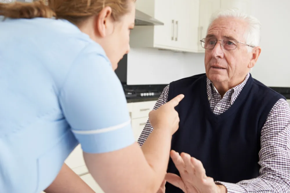 Foto de enfermera señalando con un dedo a un anciano con cara seria