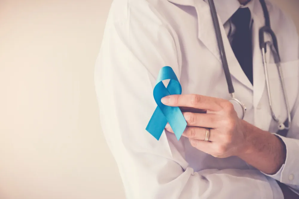 Foto de un medico que sostiene un lazo azul referente al cáncer de próstata