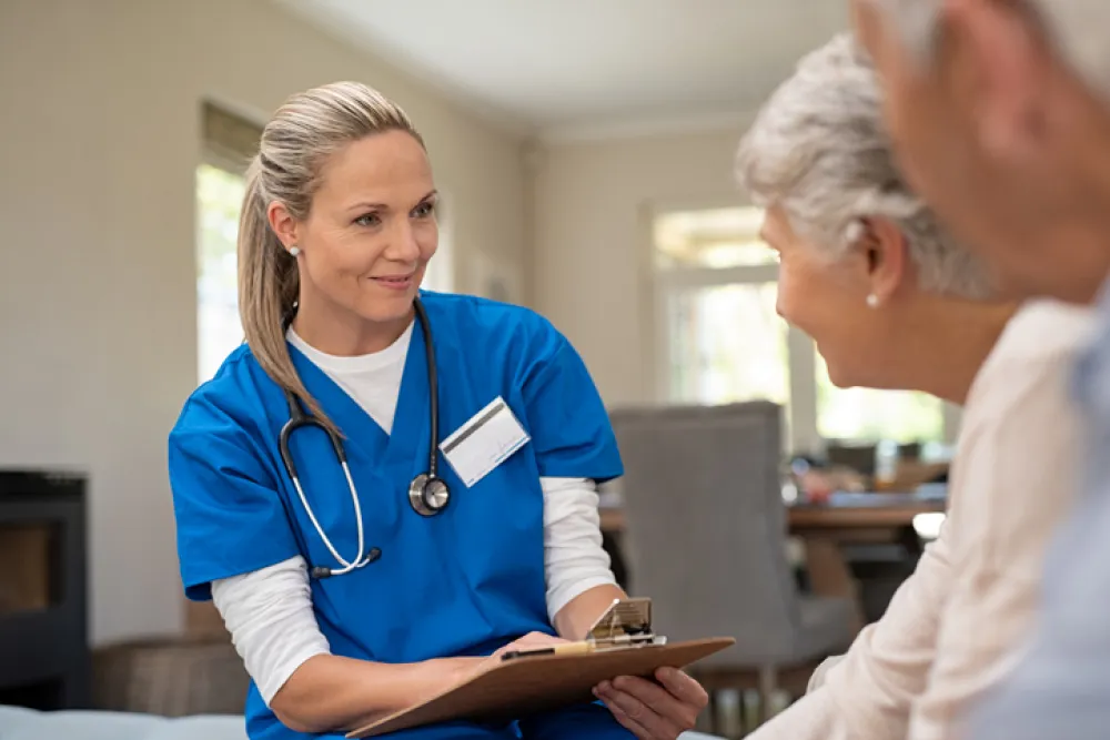 Foto de una enfermera atendiendo una conversación con una pareja de personas mayores
