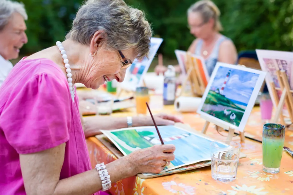 Foto de mujeres mayores sentadas mientras pintan un cuadro 